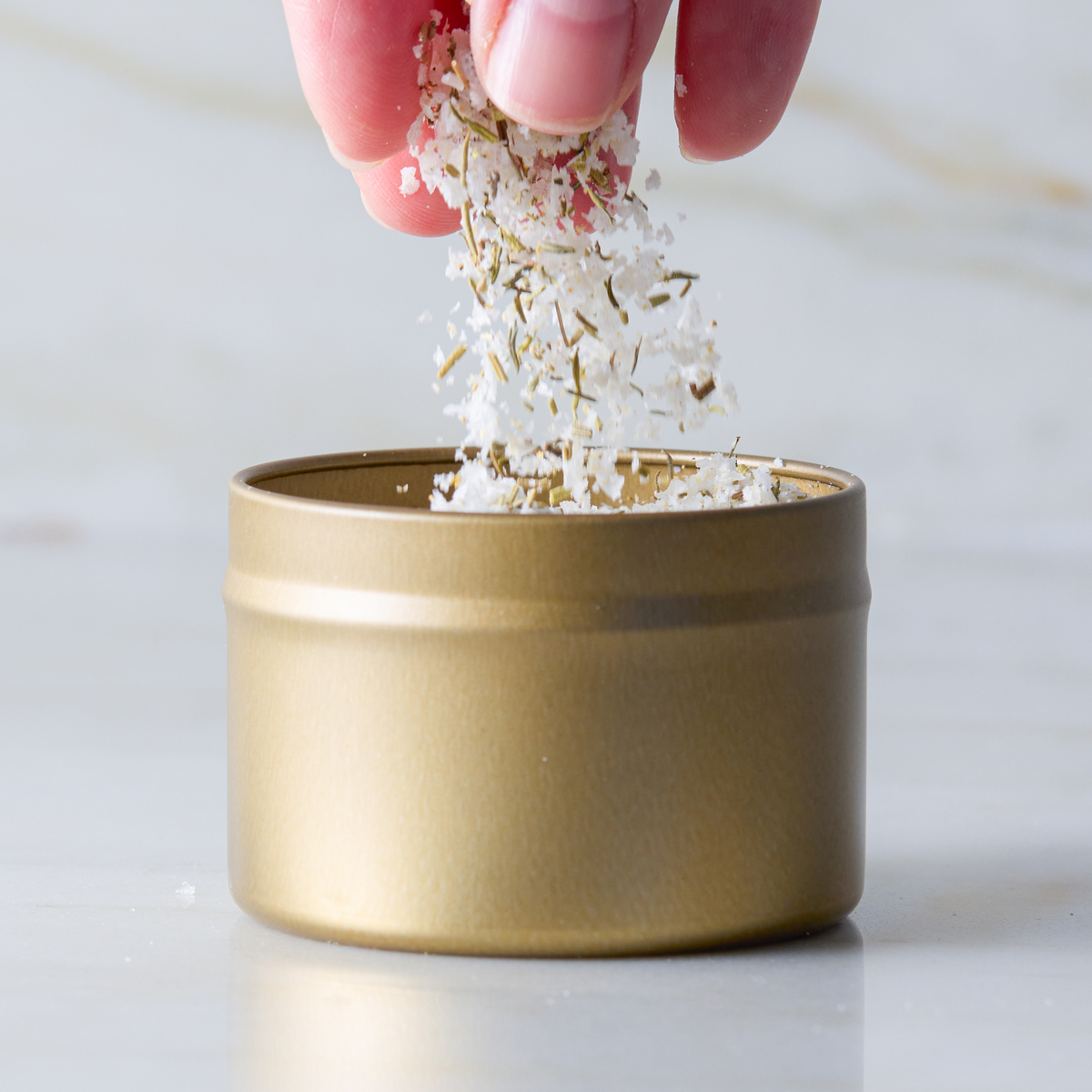 a hand pouring white flakes into a small container