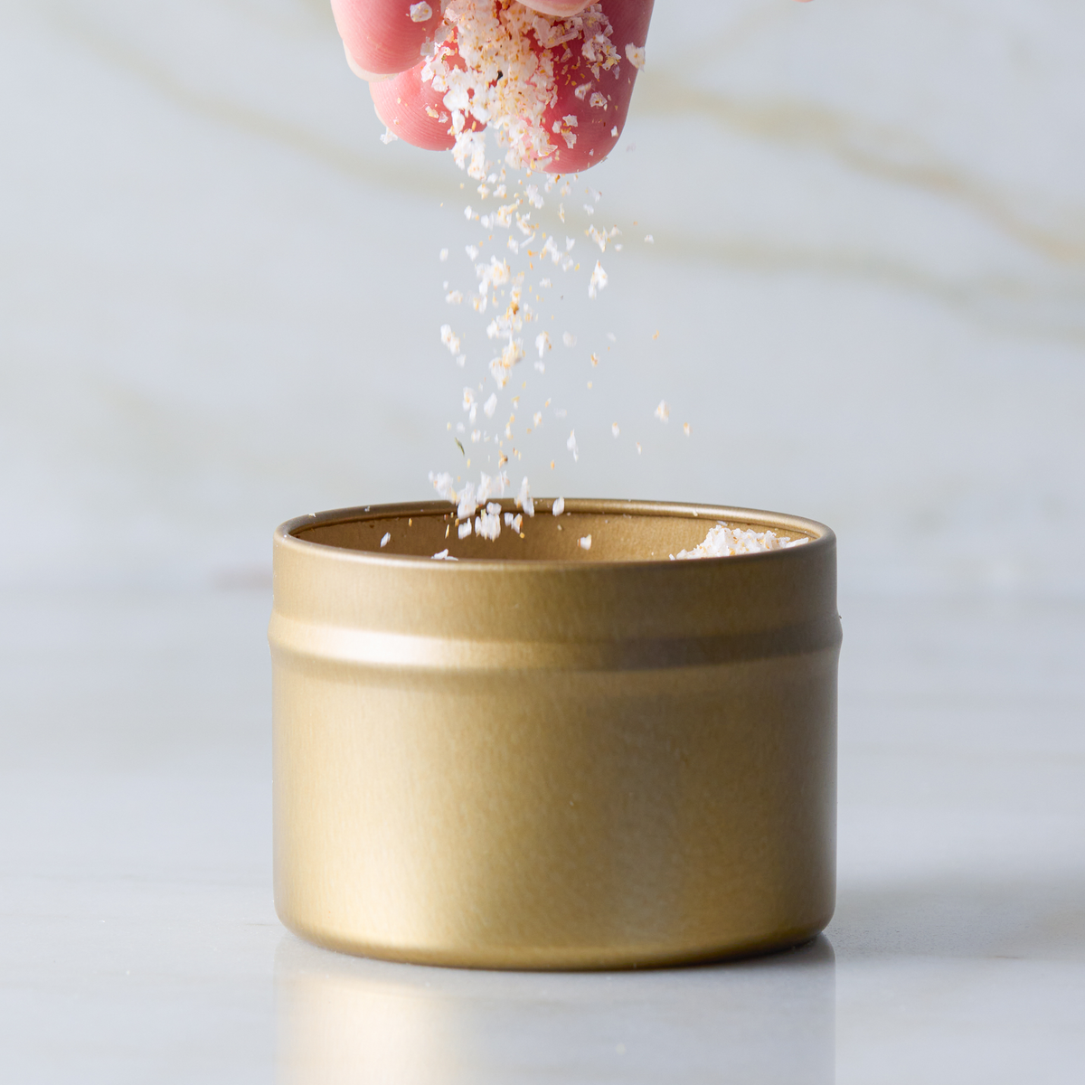 a hand pouring salt into a small container