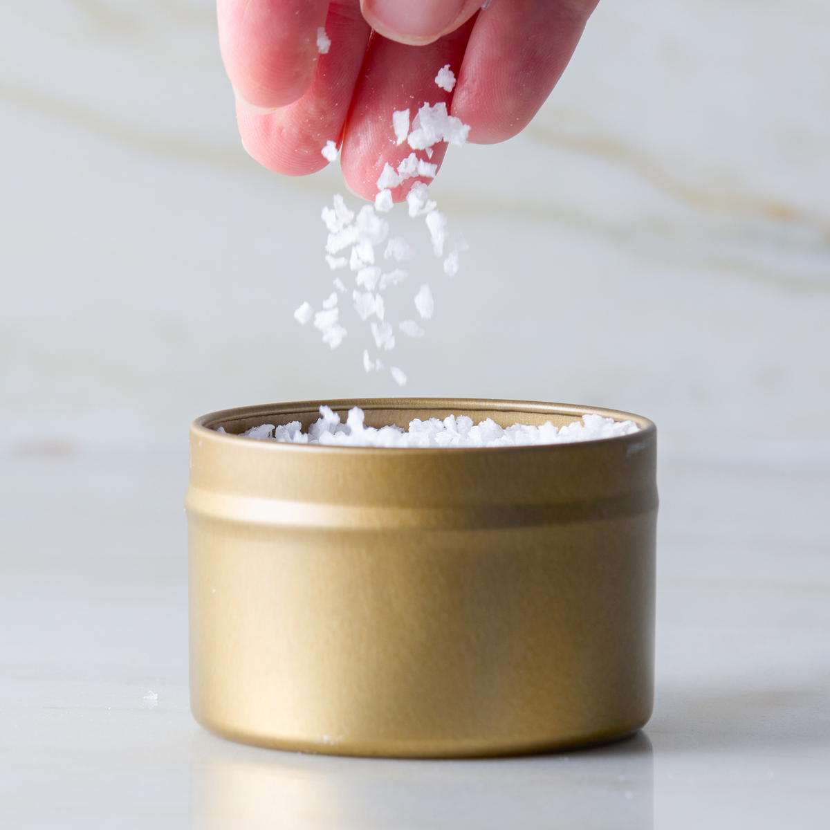 a hand pouring salt into a container
