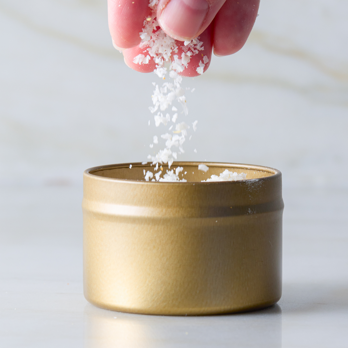 a hand pouring salt into a container