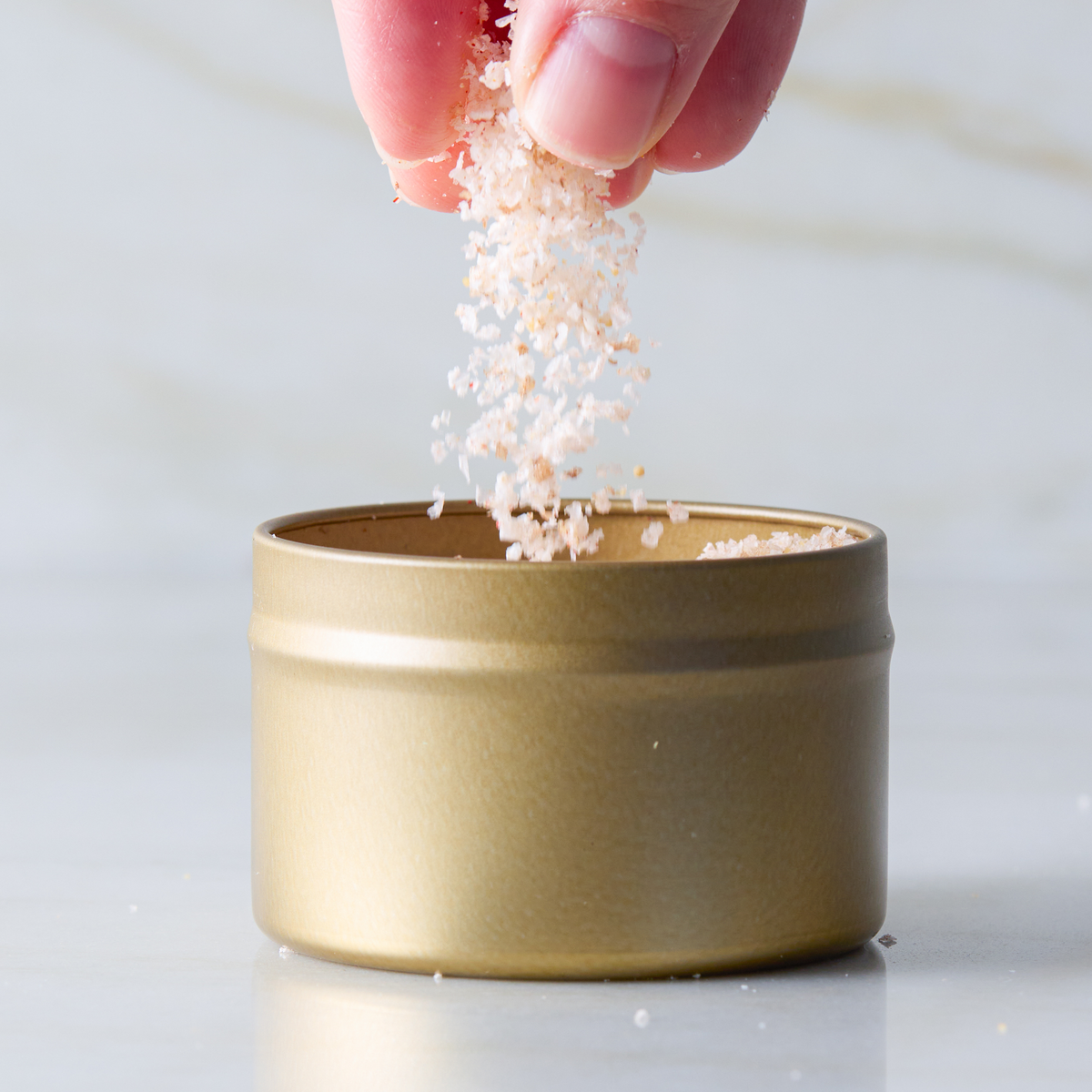 a hand pouring salt into a small container